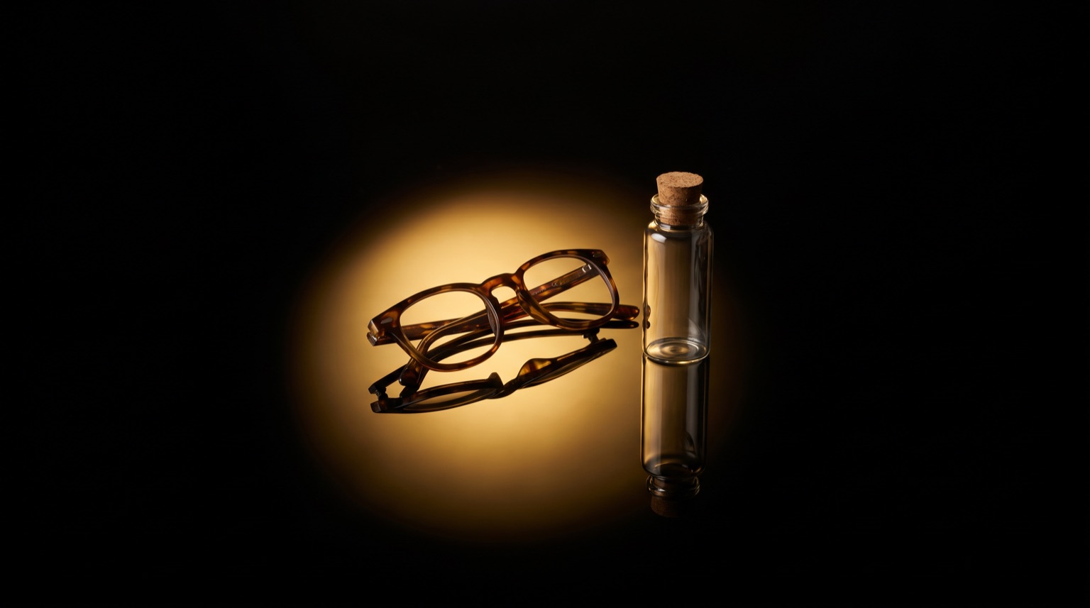 Lentes de lectura junto a un vial de investigación bajo luz dorada sobre fondo negro